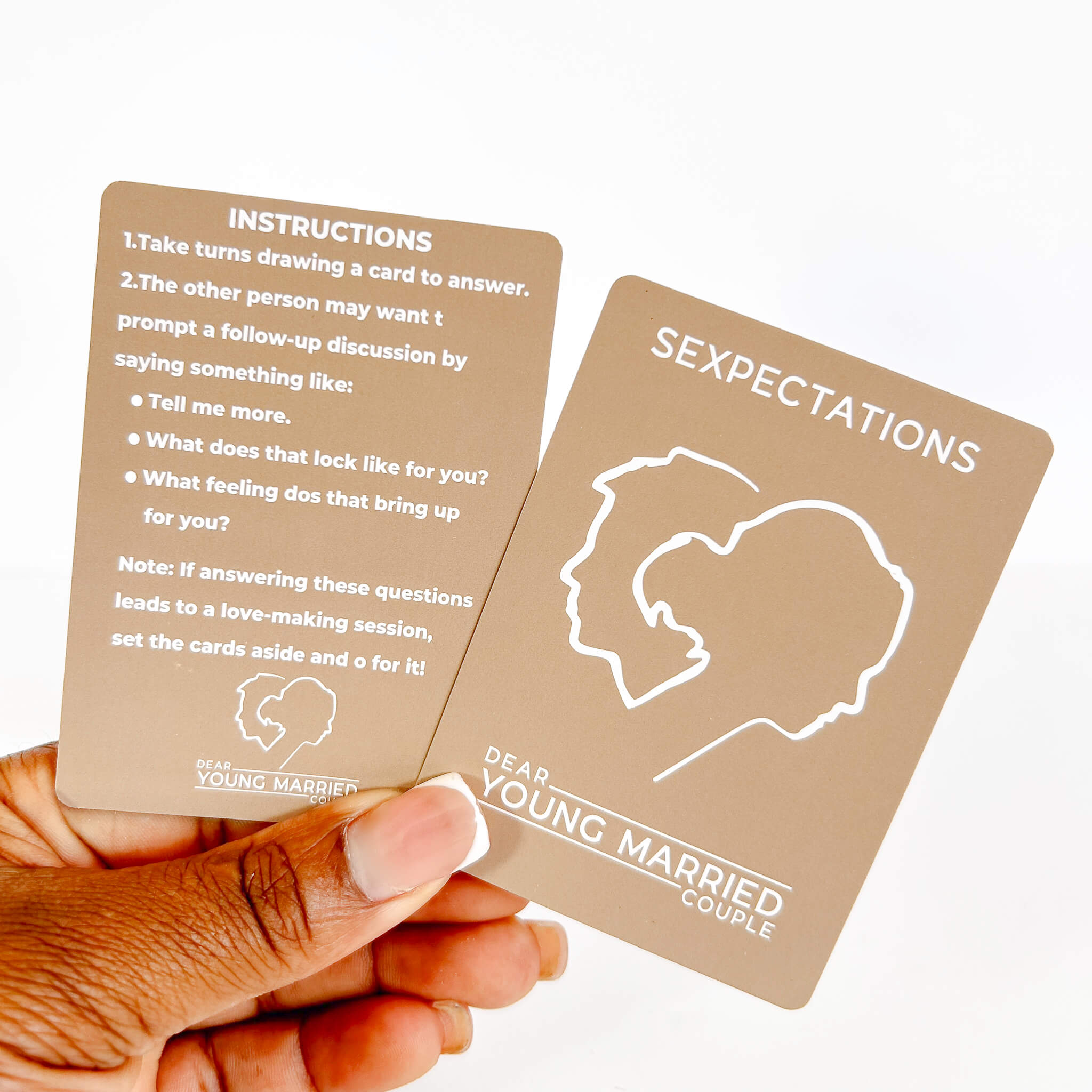 Two Sexpectations cards with instructions and a face outline, held by a hand.