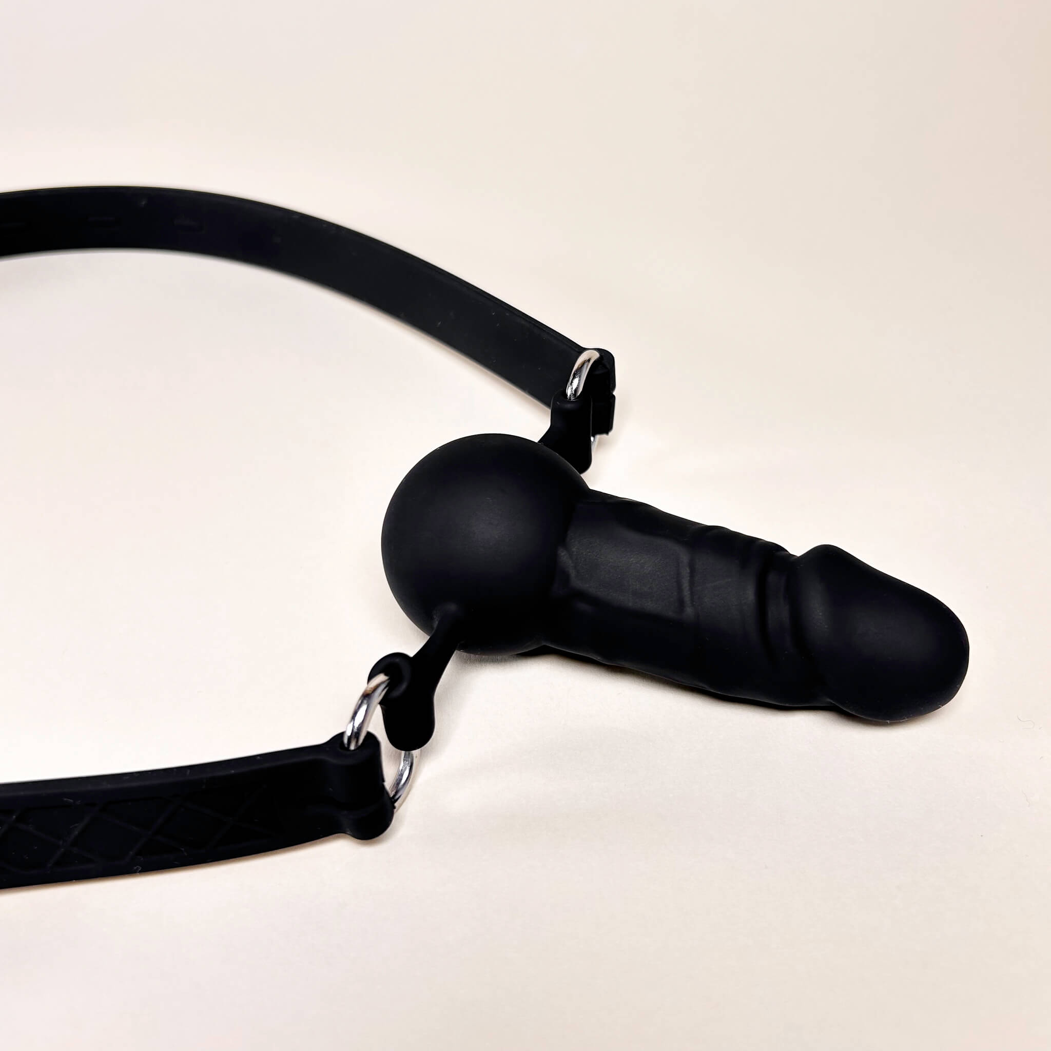 Black Silicone Dildo Mouth gag with a strap on a beige background