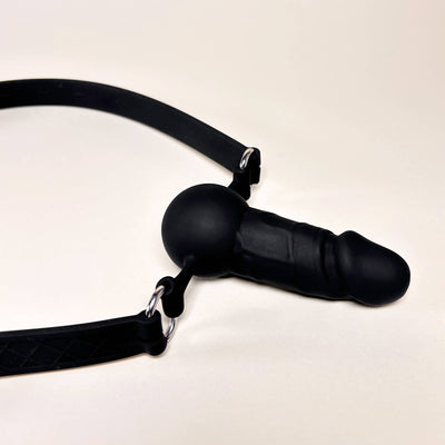 Black Silicone Dildo Mouth gag with a strap on a beige background