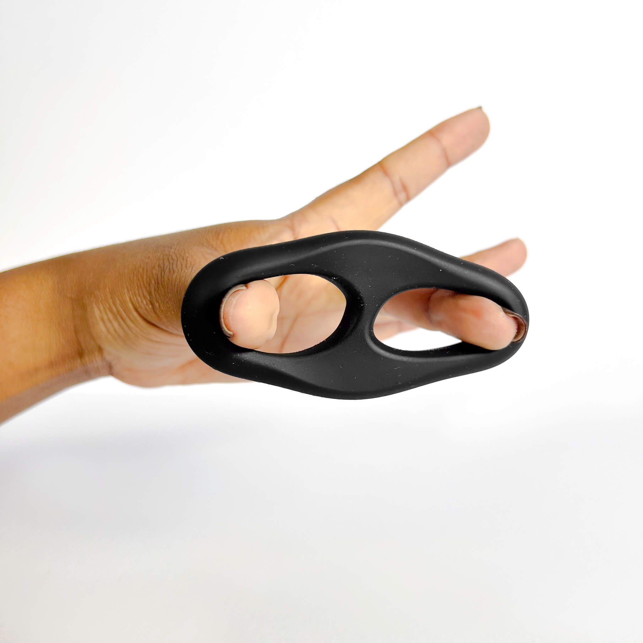 Hand holding a black Silicone Double Cock Ring against a white background