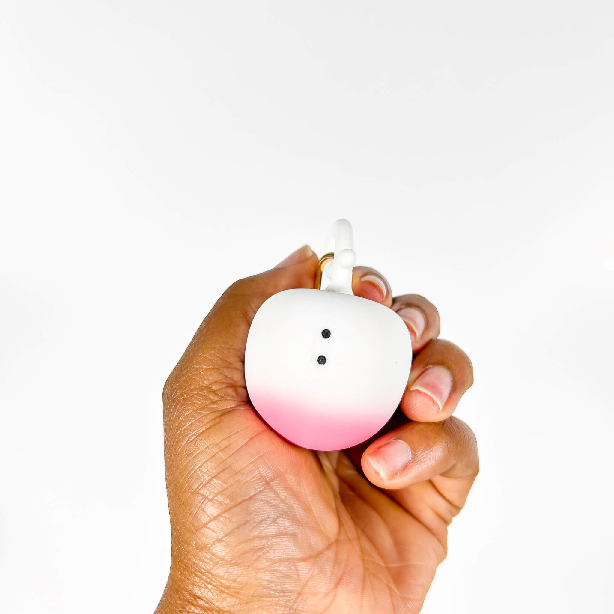 Hand holding a gradient pink to white Small Discreet Mini Vibrator against a white background