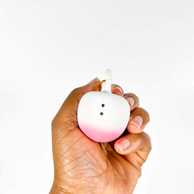 Hand holding a gradient pink to white Small Discreet Mini Vibrator against a white background