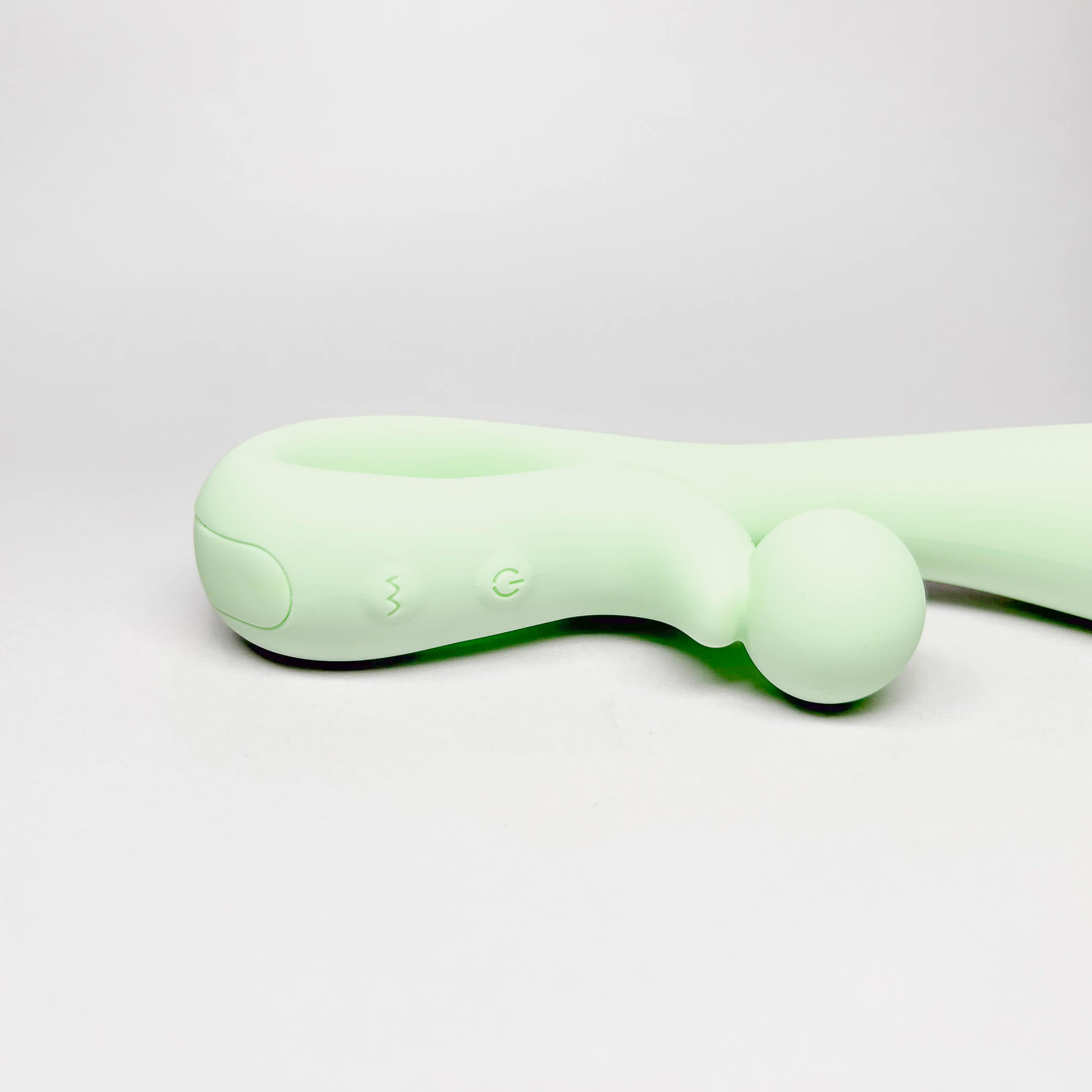 Green handheld silicone rabbit vibrator on a light grey background