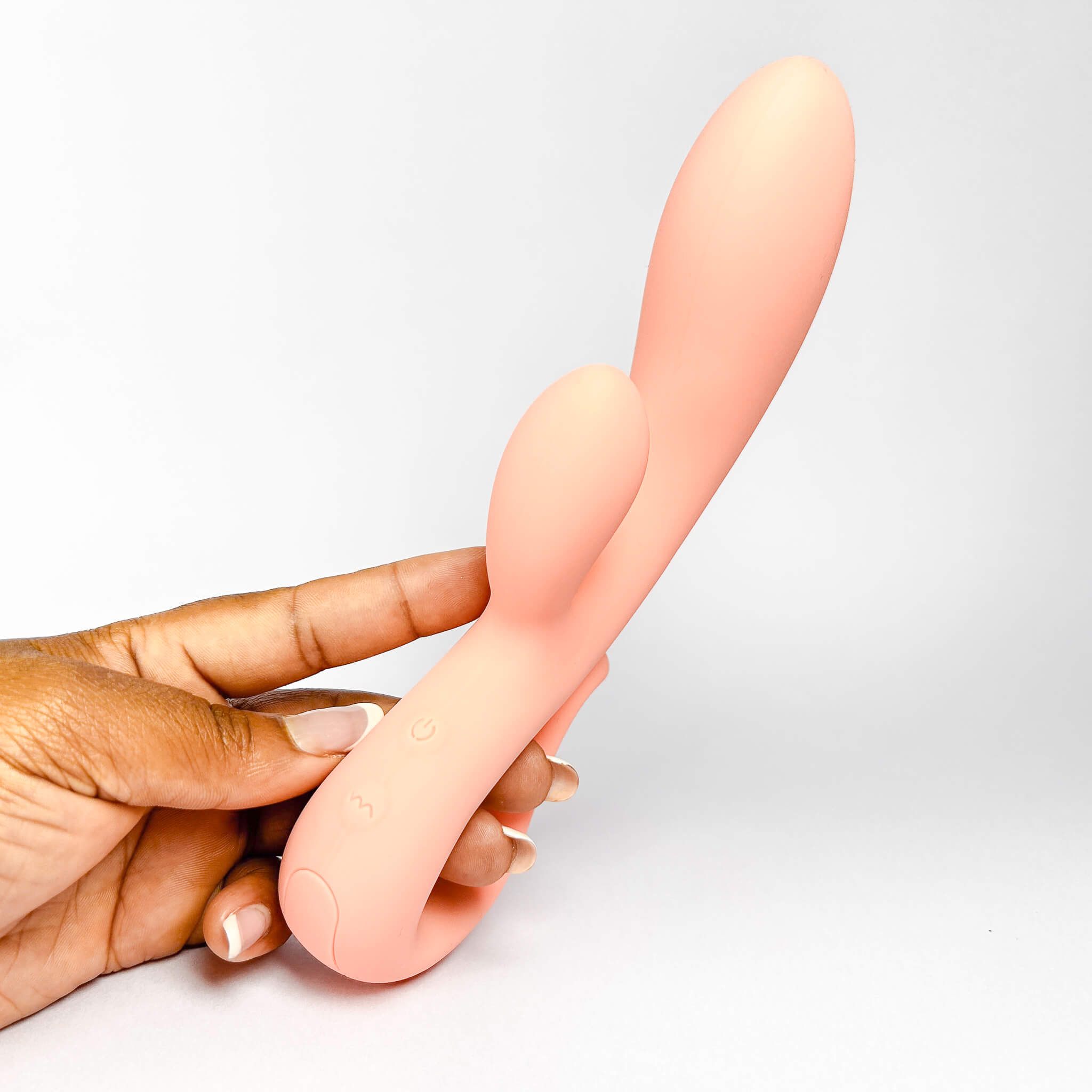 Hand holding a silicone vibrator against a plain background