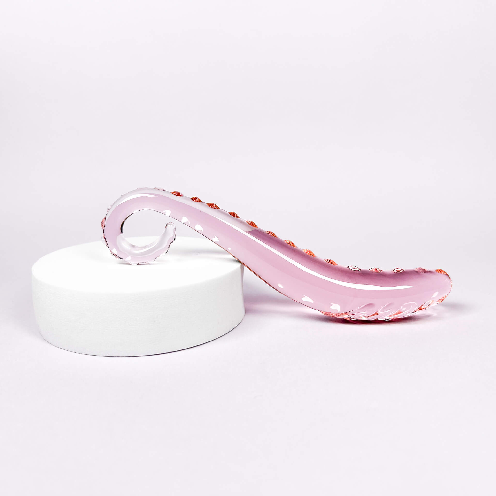 Temptacle Curved Glass Dildo (16cm) on a white pedestal with a white background