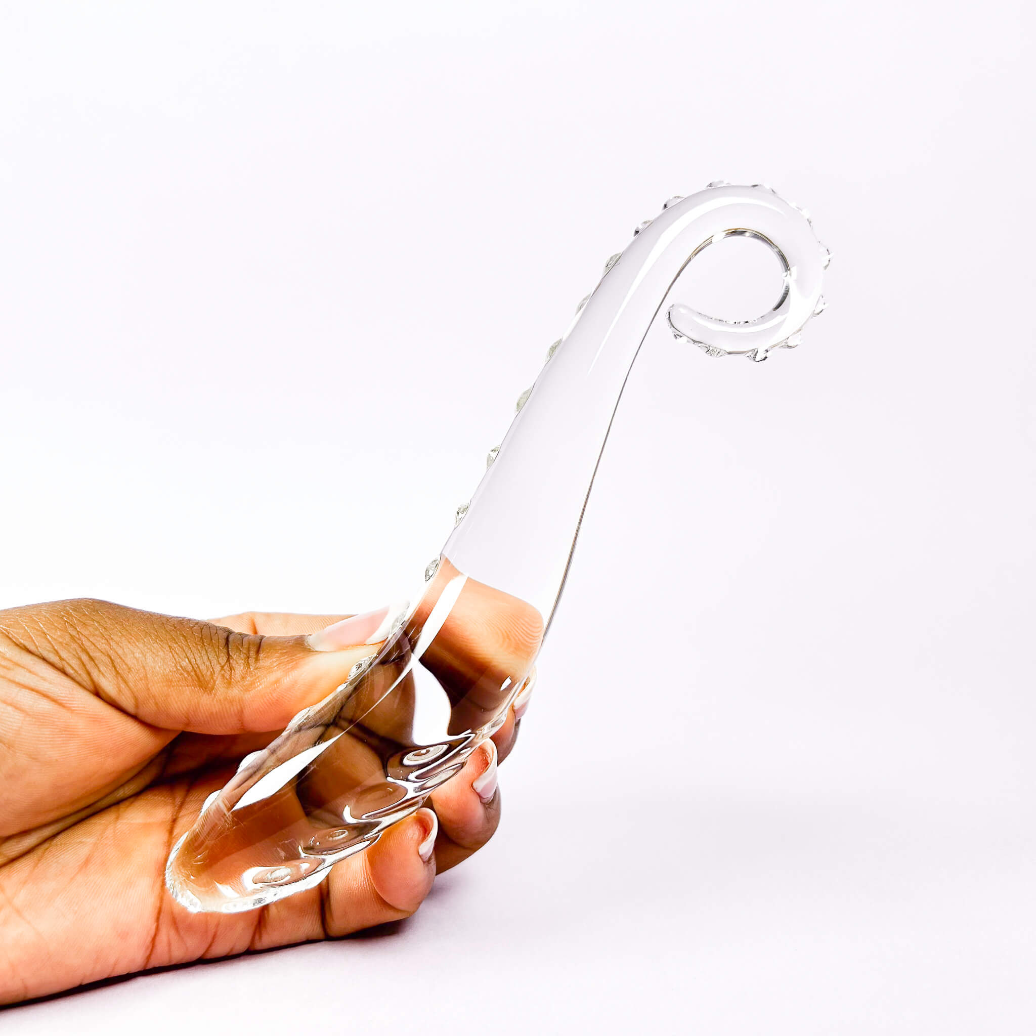 Clearglass dildo held by a hand on a white background