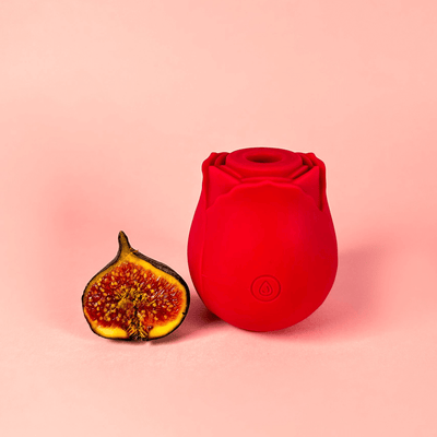 Red rose vibrator and half-cut fig on a pink background