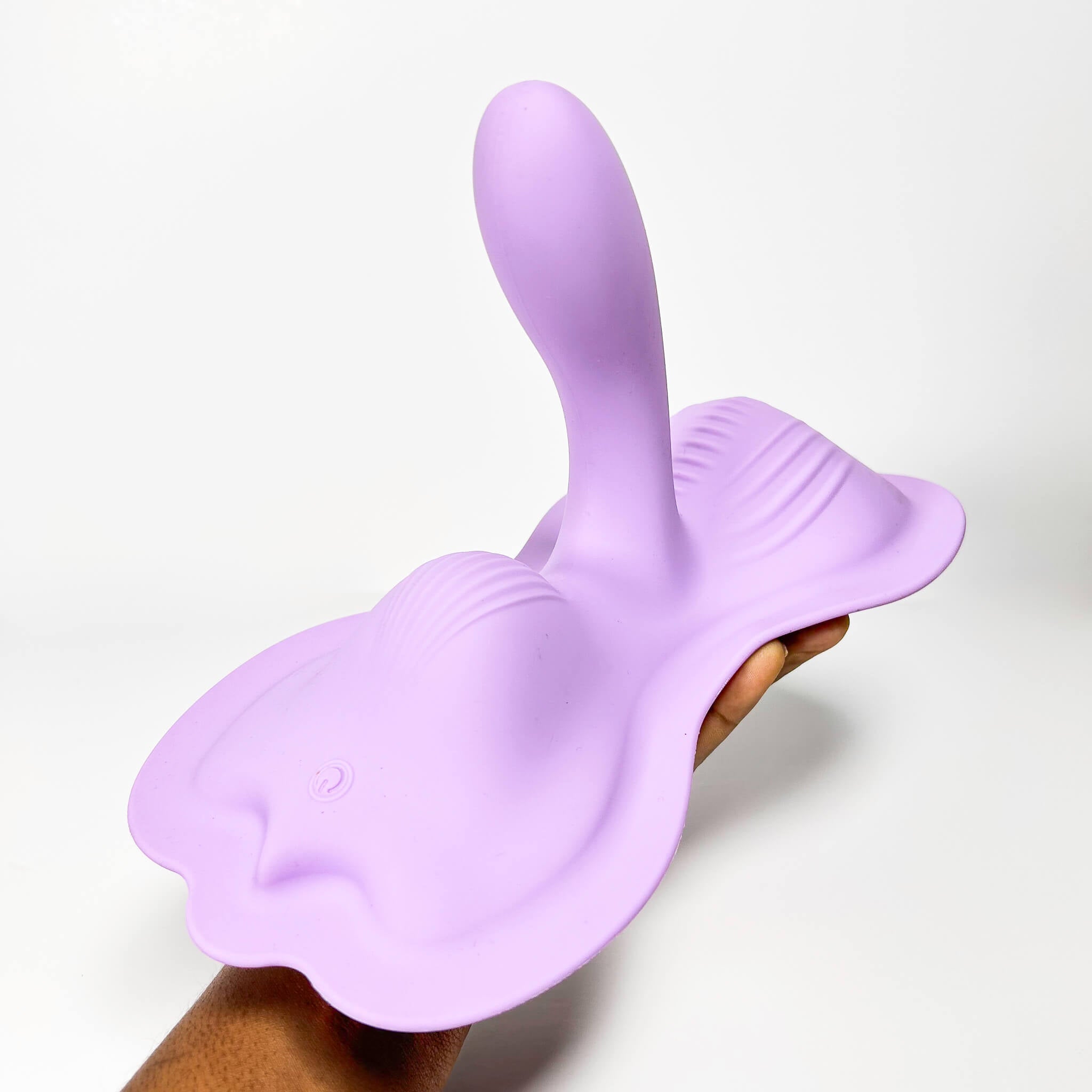 Purple silicone Triple Tease Cowgirl Cushion Vibrator App Controlled held by a hand on a white background