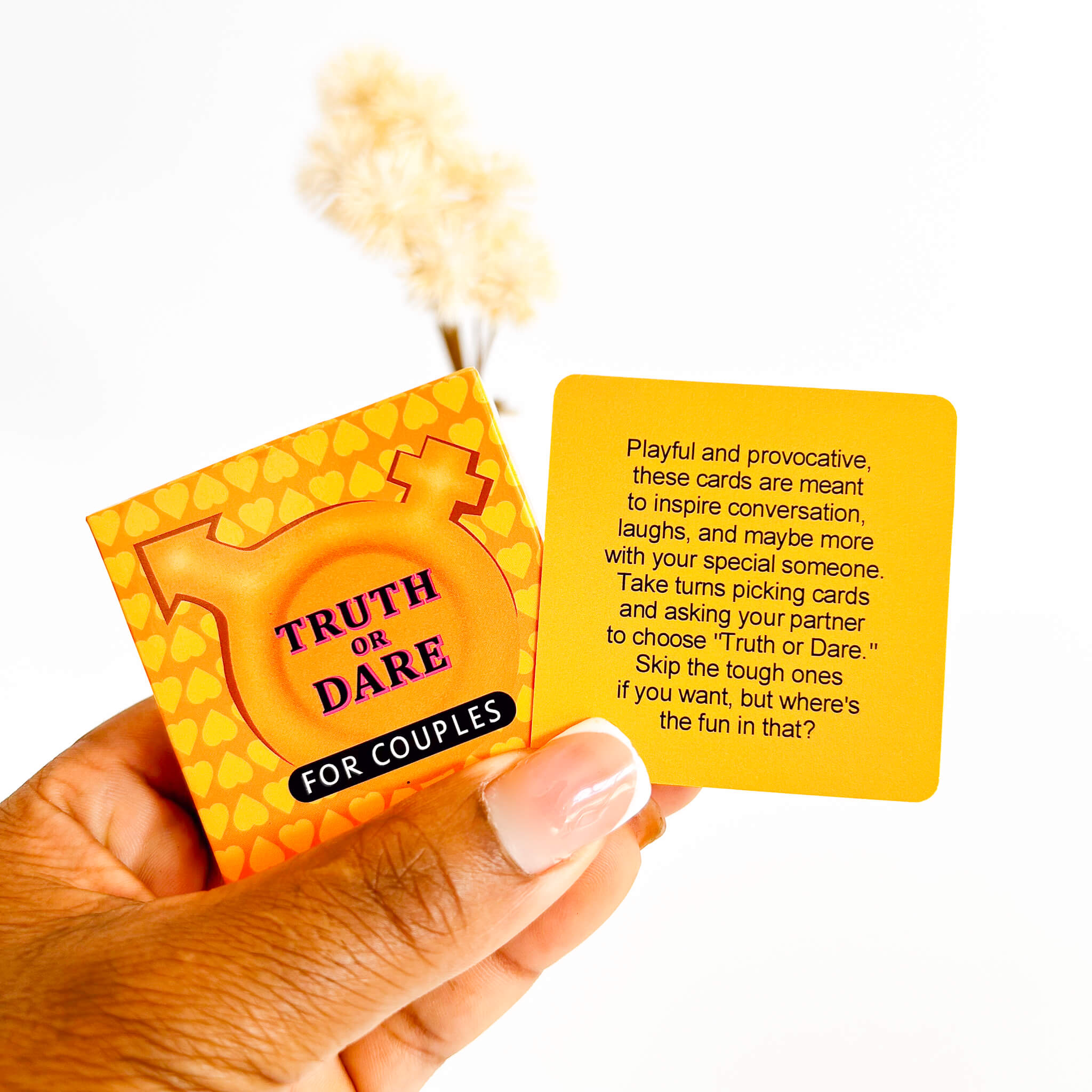 Hand holding 'Truth or Dare for Couples' card game packaging with text on a white background