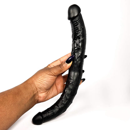 Black flexible Tapered Double Ended Dildo held by a hand with dark nail polish on a white background