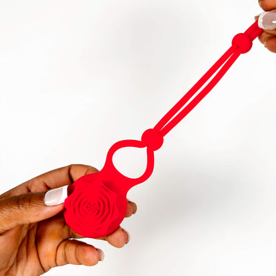 Red silicone band with a white button held by a hand on a white background