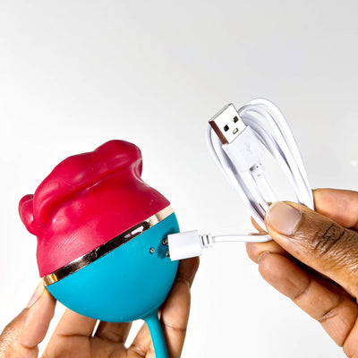 Colorful big mouth licking vibrator  device with USB cables being held by a hand on a white background