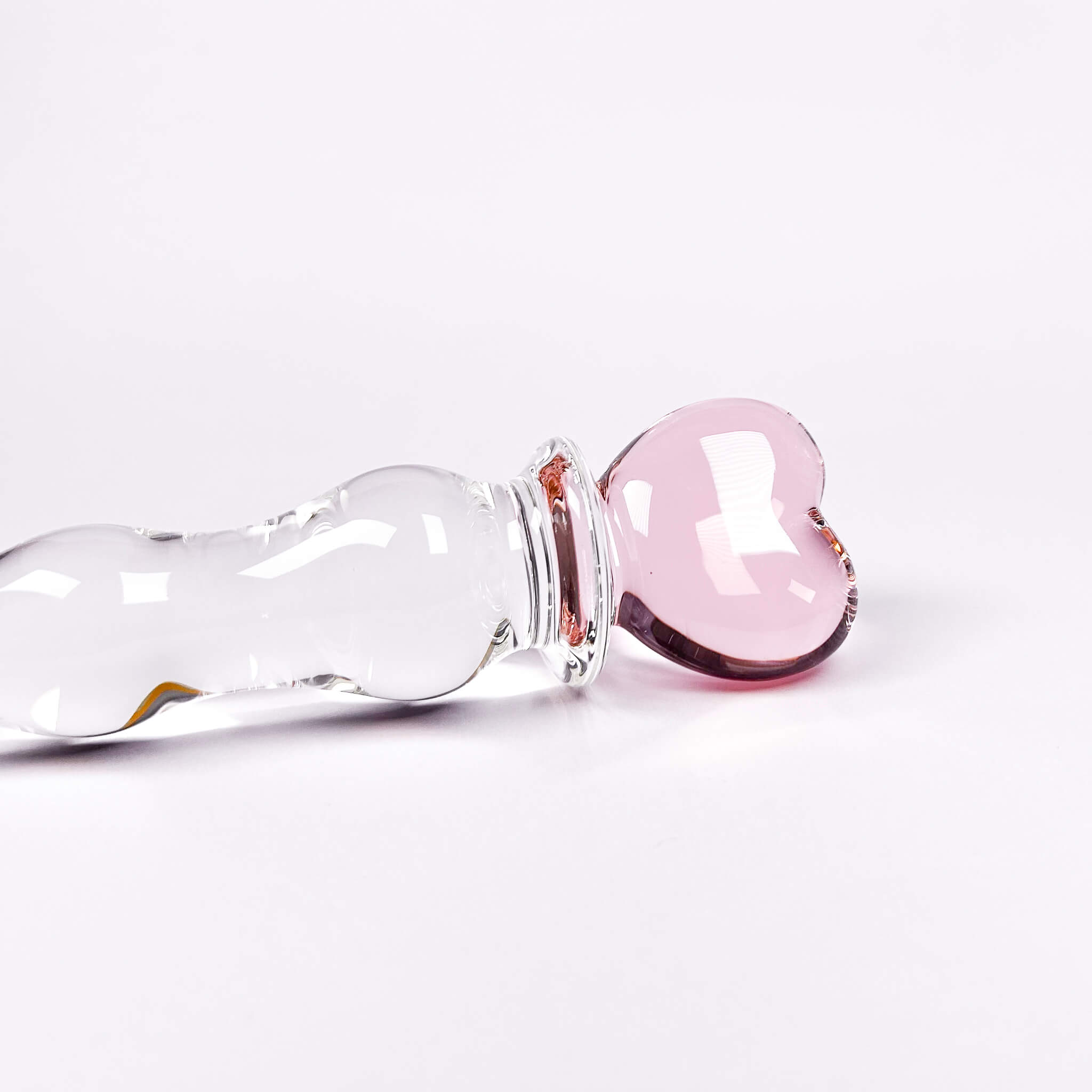 Glass dildo with a pink stopper on a white background