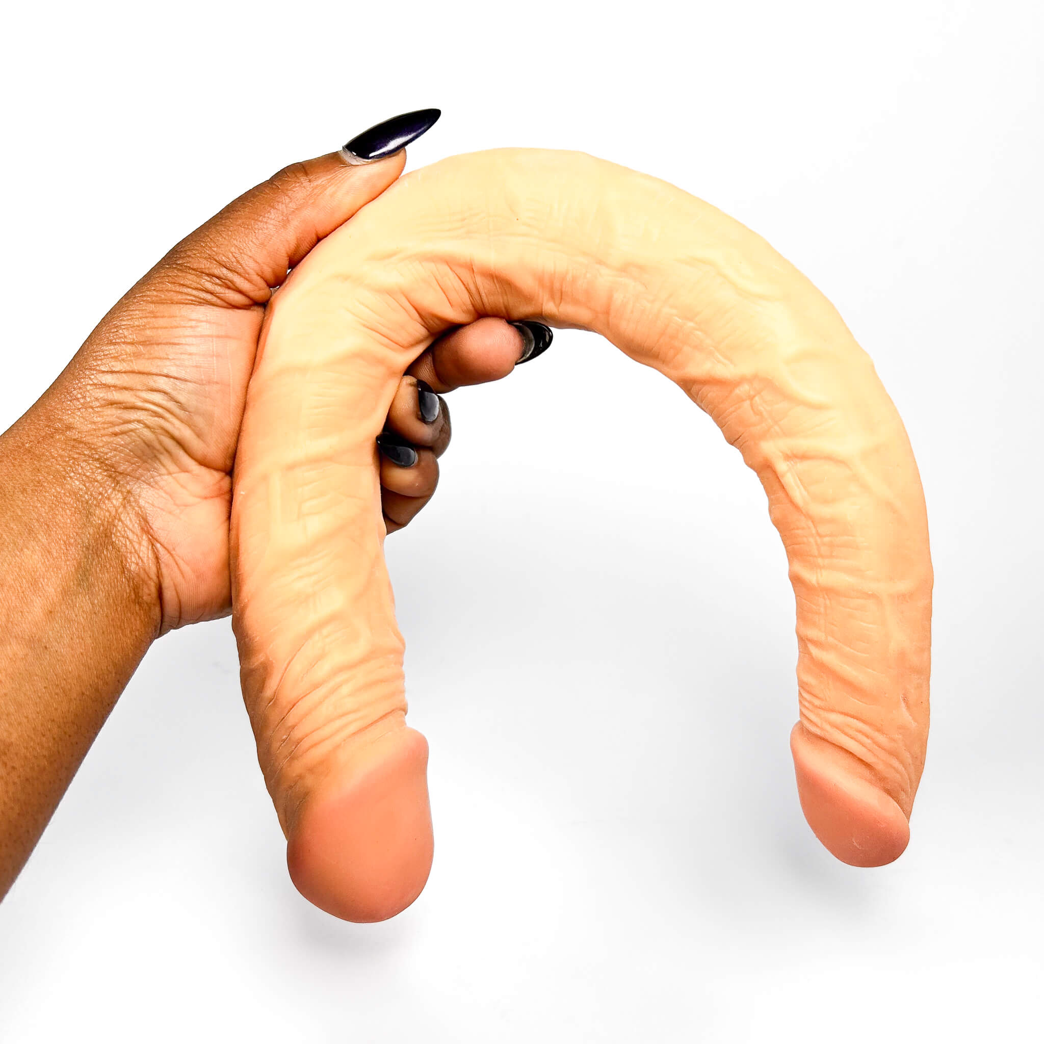 Hand holding a large, double-sided dildo against a white background