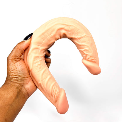 Hand holding a lesbian dildo against a white background