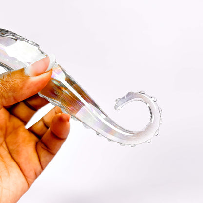 Clear glass dildo held by a hand on a white background