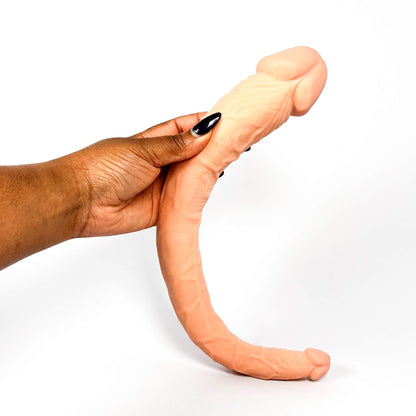 Hand holding a double ended dildo against a white background