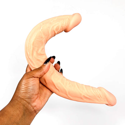 Hand holding a double headed dildo against a white background