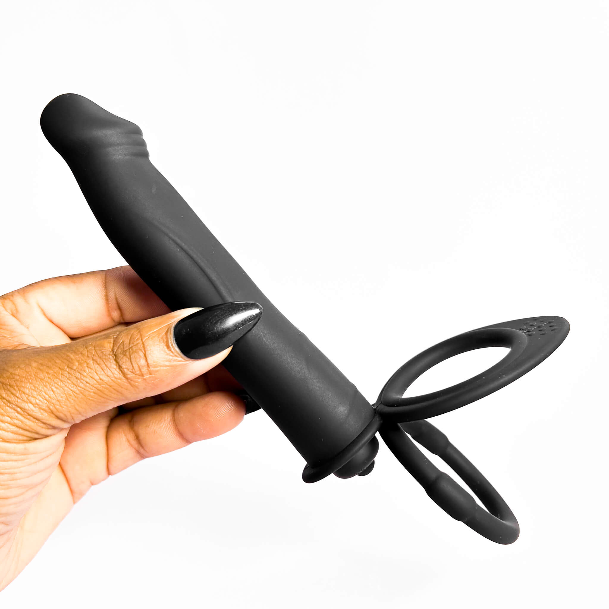 double penetration cock ring held by a hand on a white background