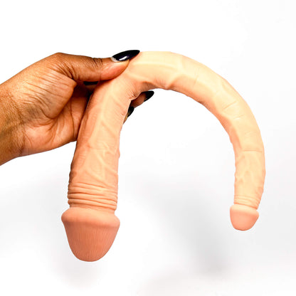Hand holding a sflexible double ended dildo on a white background