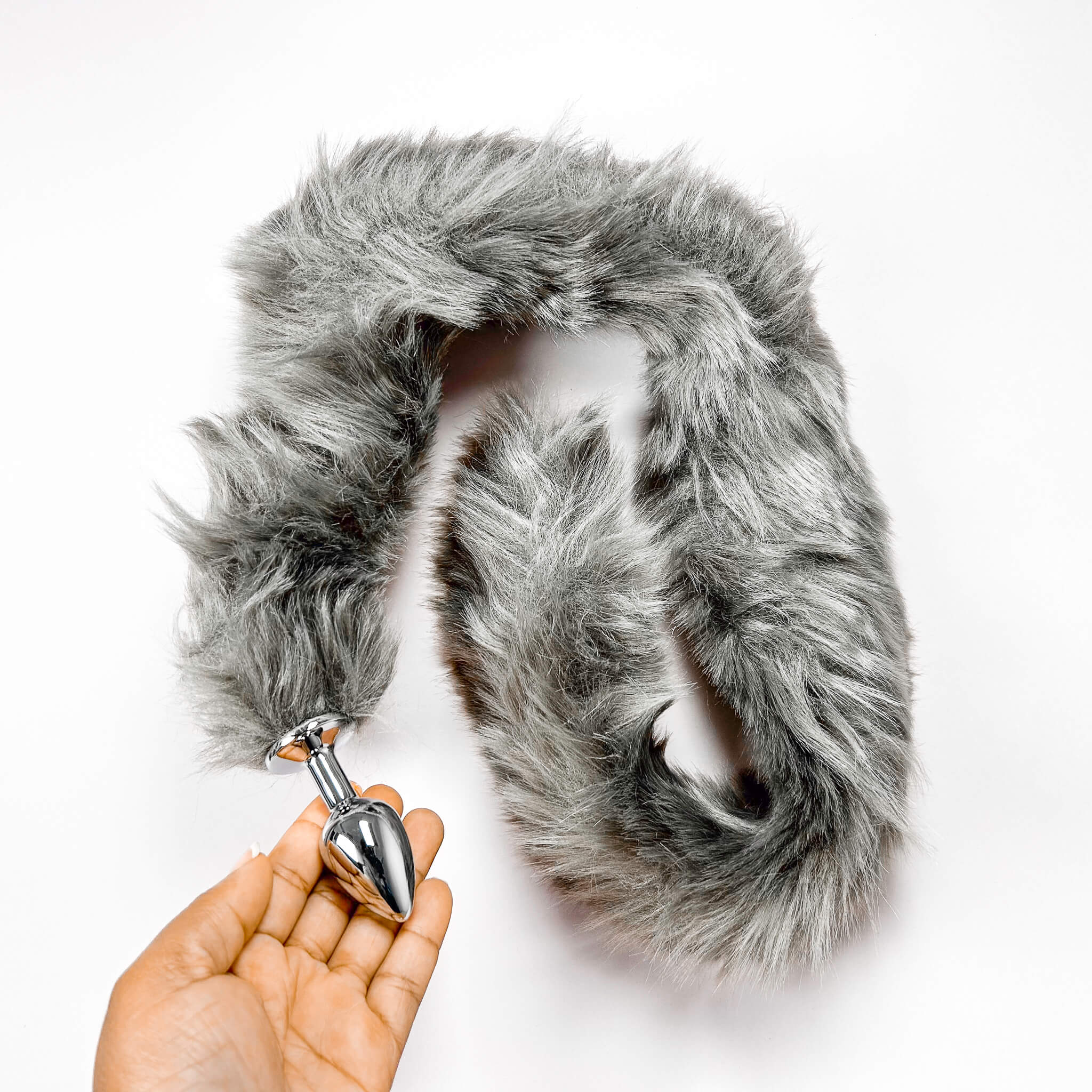 grey Extra Long Tail With Metal Butt Plug by a hand on a white background