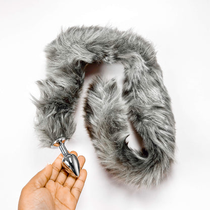 grey Extra Long Tail With Metal Butt Plug by a hand on a white background
