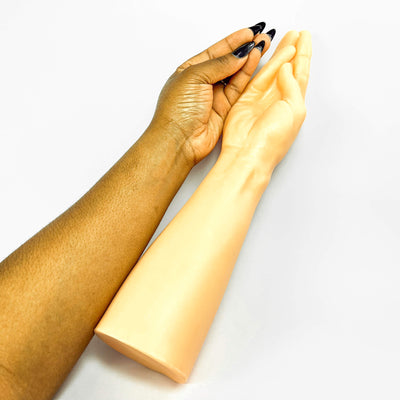 Two hands, one with dark skin and the other with light skin, holding a hand dildo against a white background.