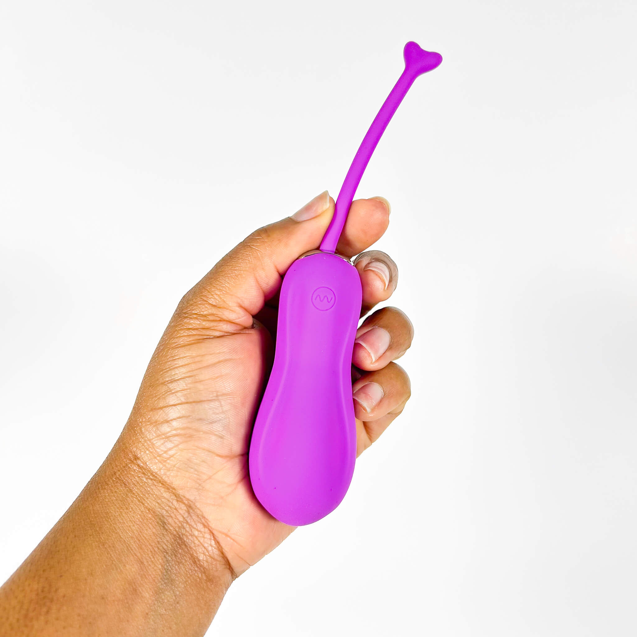 Hand holding a purple insertable remote egg vibrator against a white background