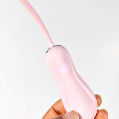  insertable vibrator pink held in a hand against a light gray background