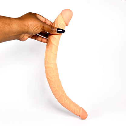 Hand holding a long, flexible, long double sided dildo against a white background