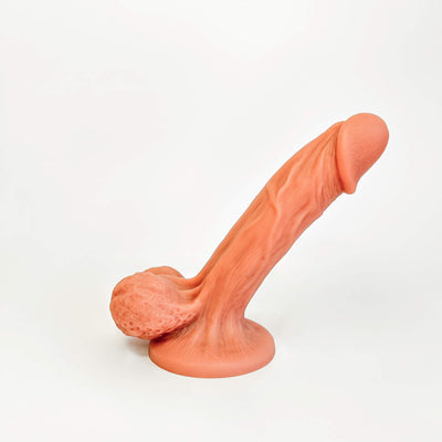 A realistic silicone dildo in a peachy orange color, photographed on a clean white background.