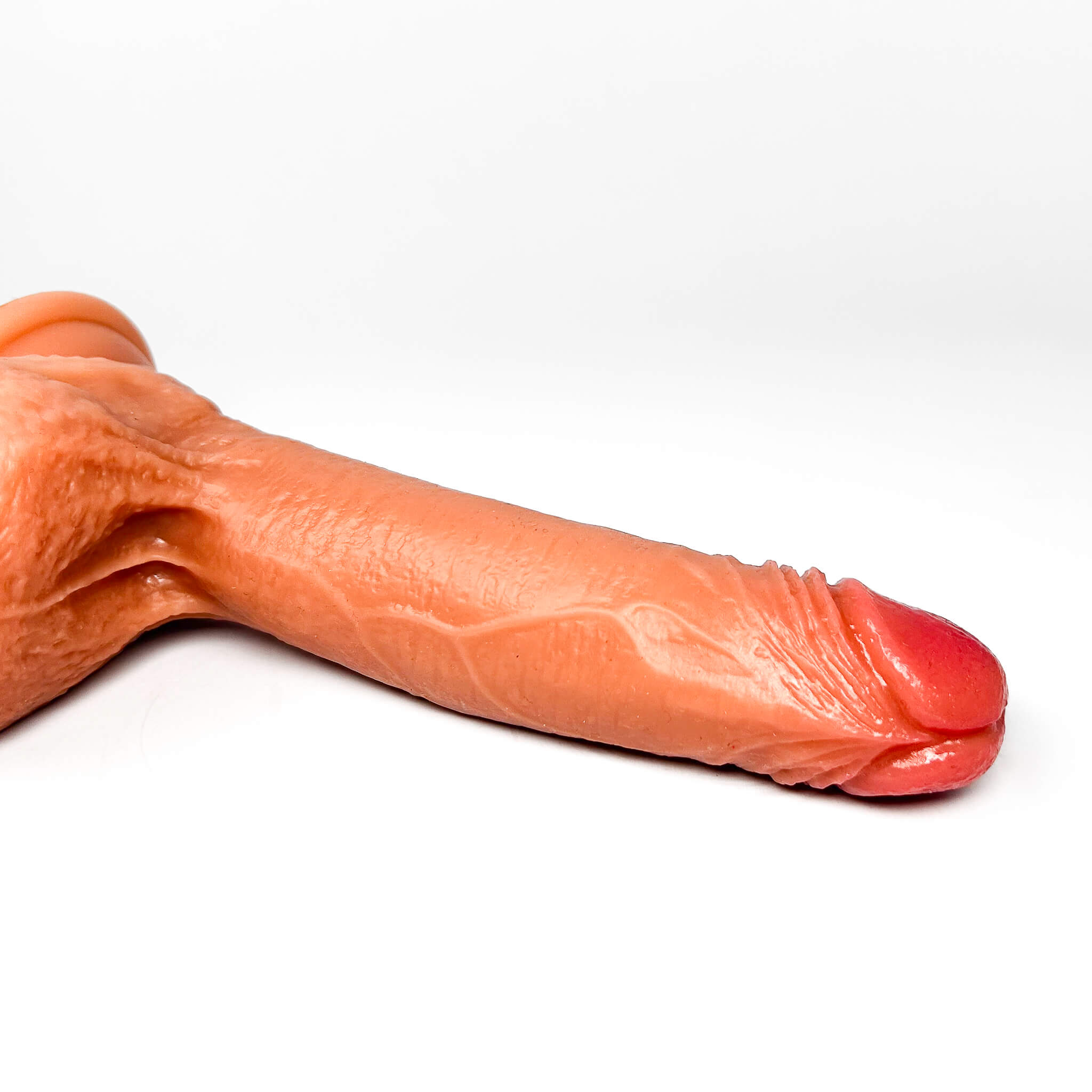 Close-up of a realistic silicone dildo of a human penis on a white background