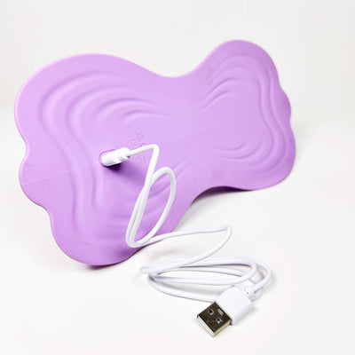 Purple riding vibrator with a white USB cable on a white background