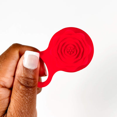 rose adjustable vibrating cock ring held by a hand on a white background