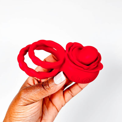 Red rose tongue cock ring held in a hand against a white background