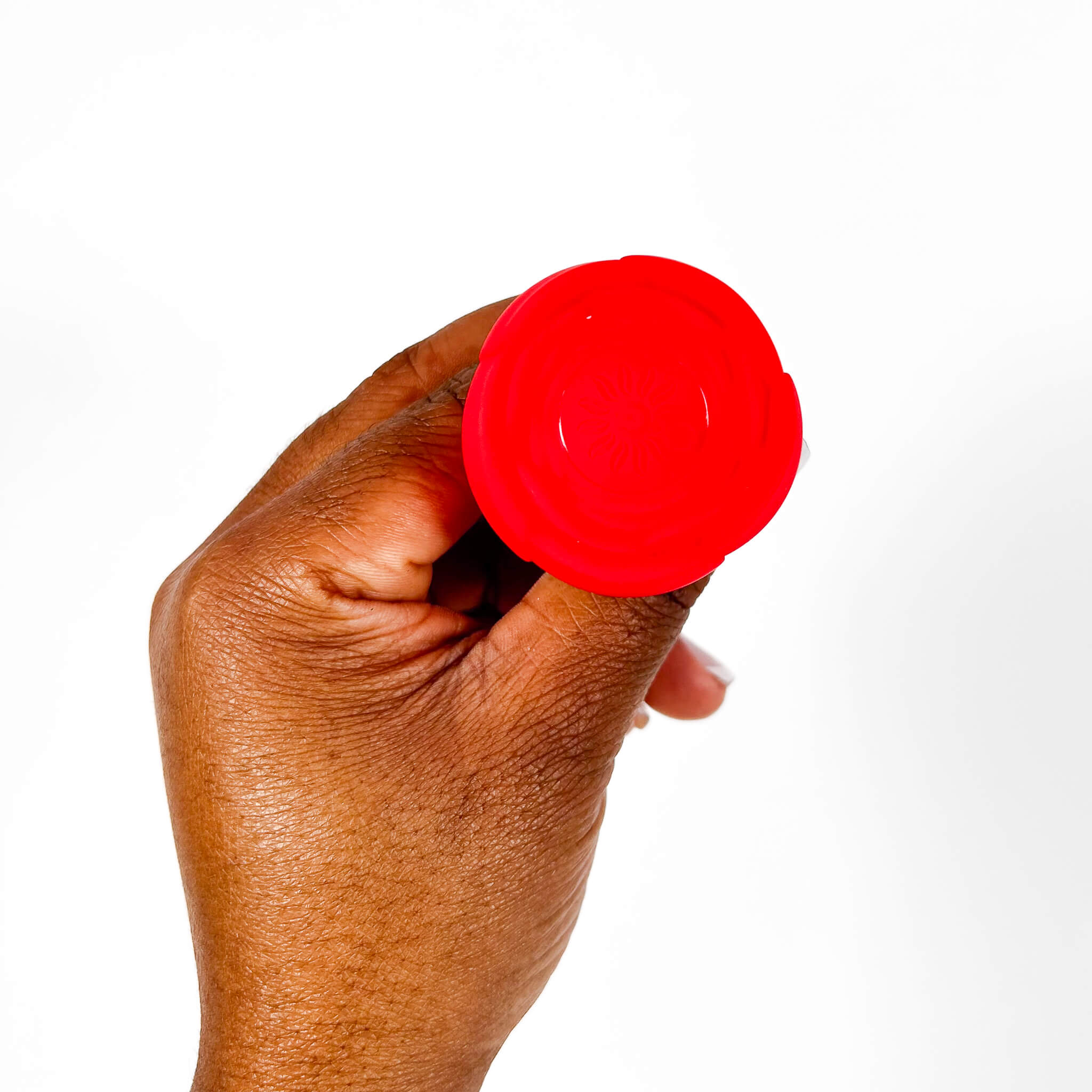 Hand holding a red rose vibrating remote butt plug against a white background