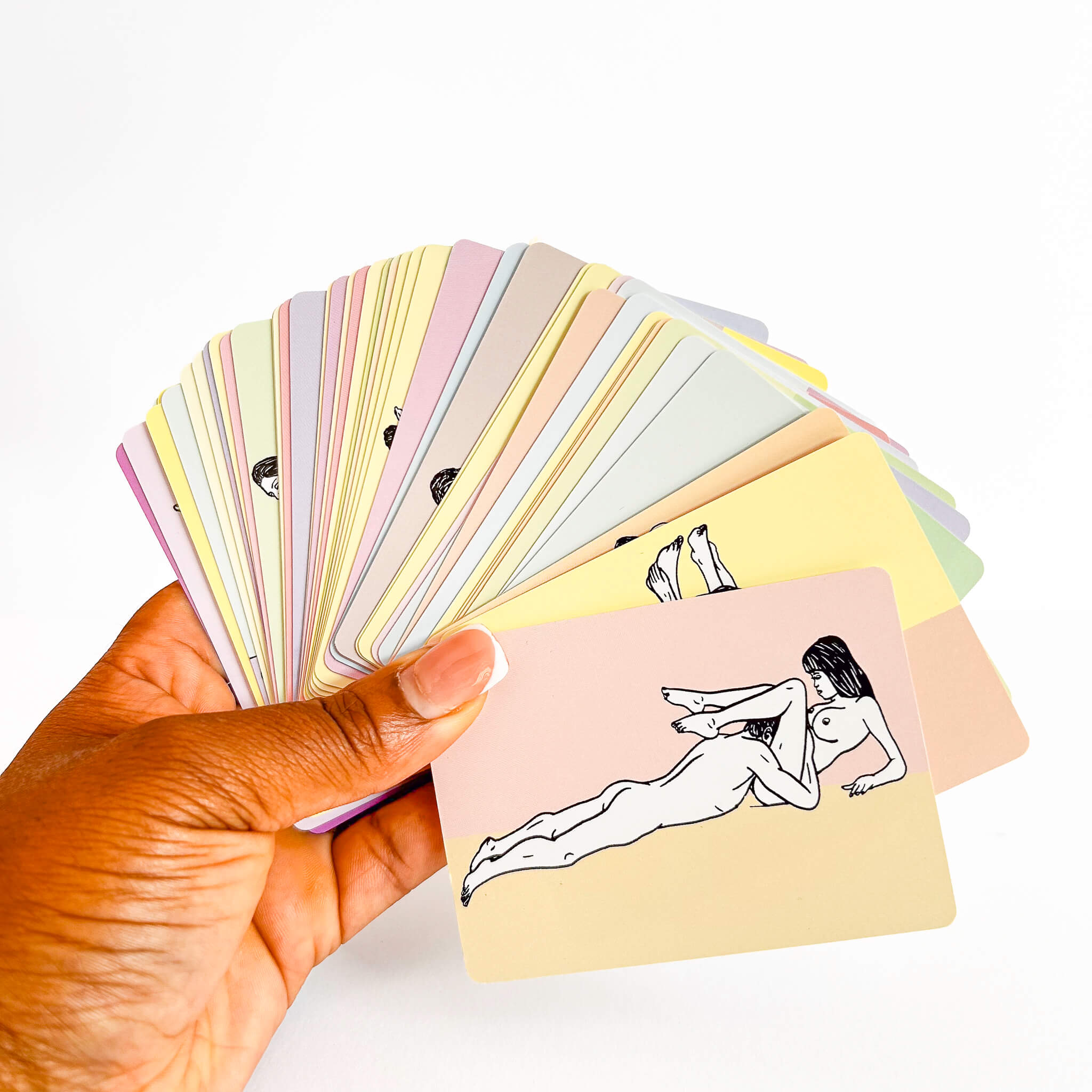 Hand holding a deck of sexual position cards with illustrated cards, including a nude illustration on one card.