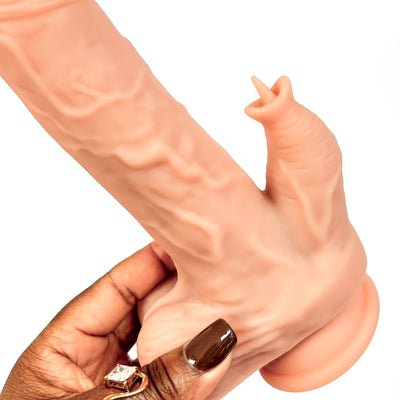 A realistic flesh-toned dildo with textured detailing, shown being held by a hand with dark brown nail polish and a ring against a plain white background.