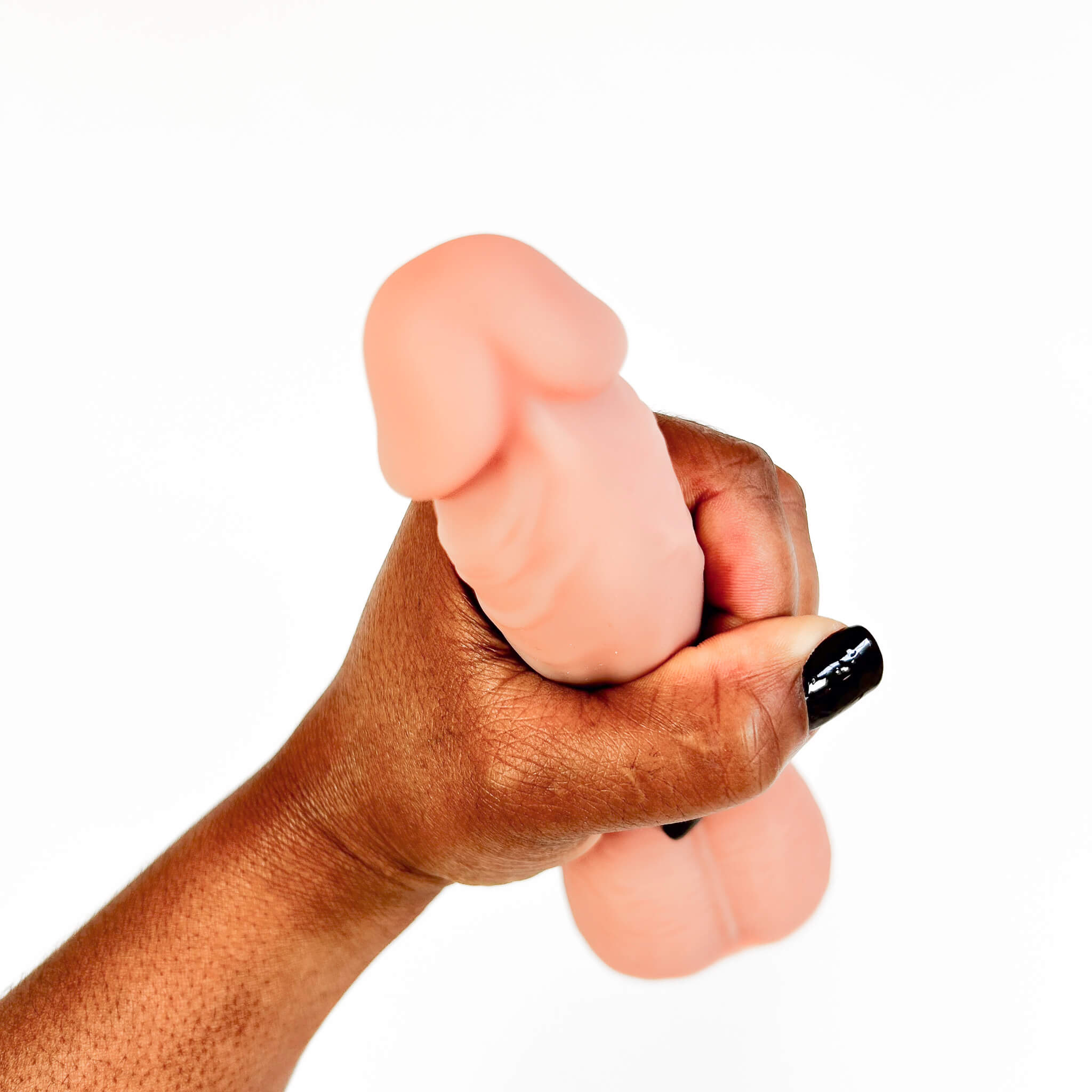 A hand with black nail polish grips a flesh-toned silicone adult novelty item against a plain white background.