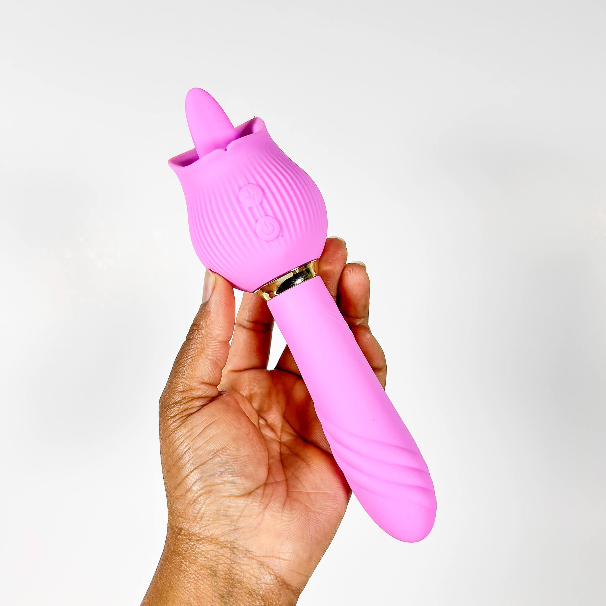 Pink silicone tongue sex toy held in a hand against a white background