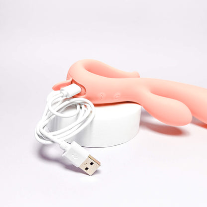 Pink handheld vibrator with a white USB cable on a light gray background