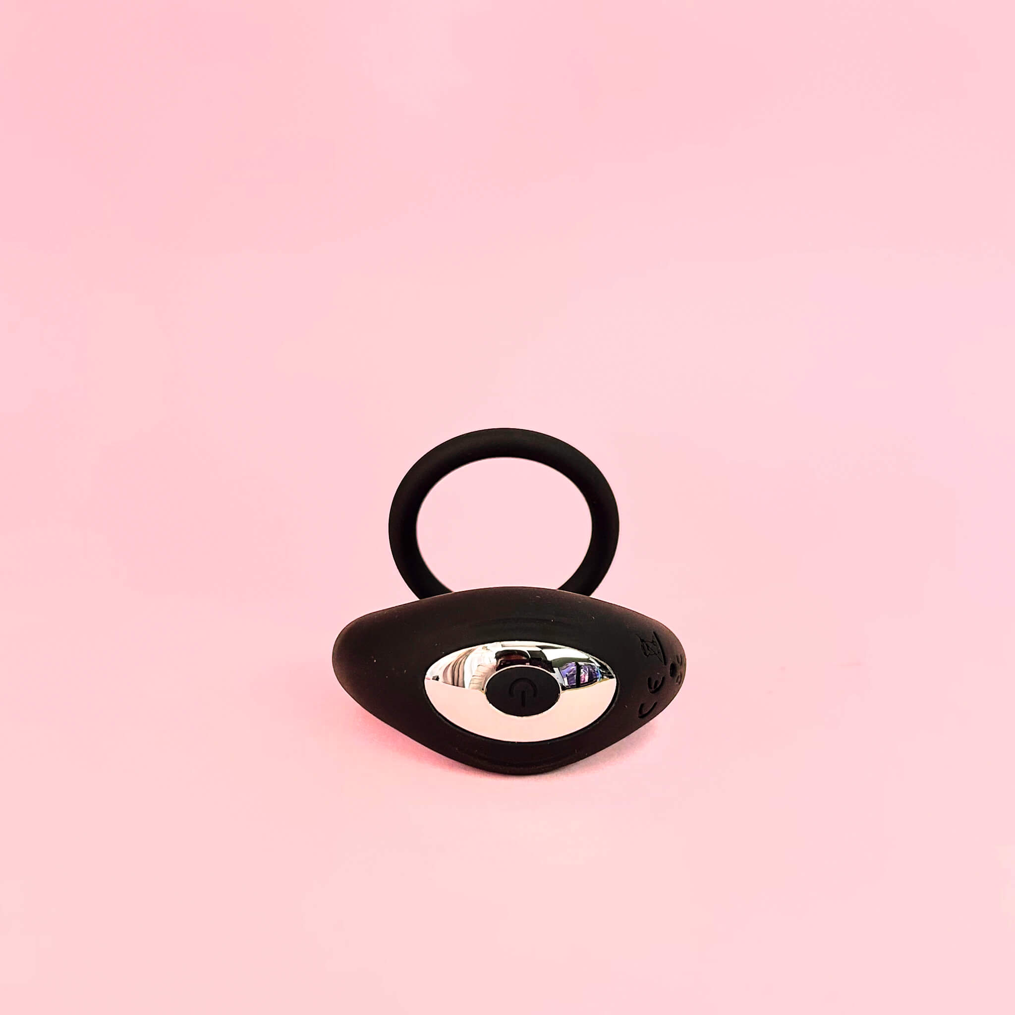 Black cock ring device with a reflective surface on a pink background