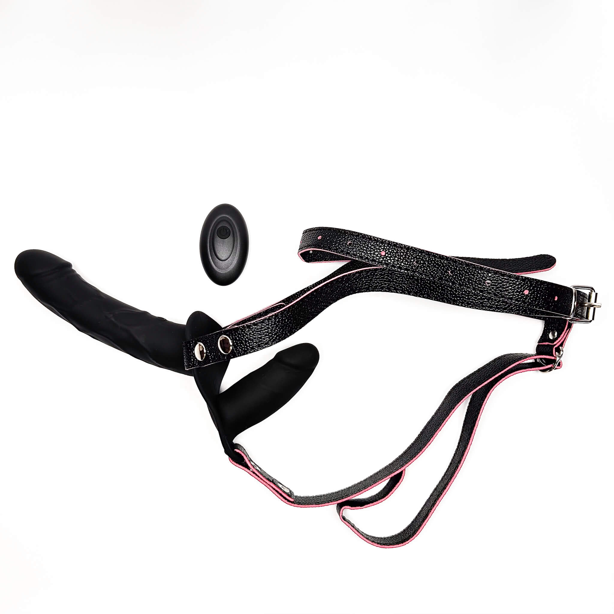 Black textured harness-style restraint with pink trim, a black padded insert, and a vibrating double strap on dildo on a plain white background.