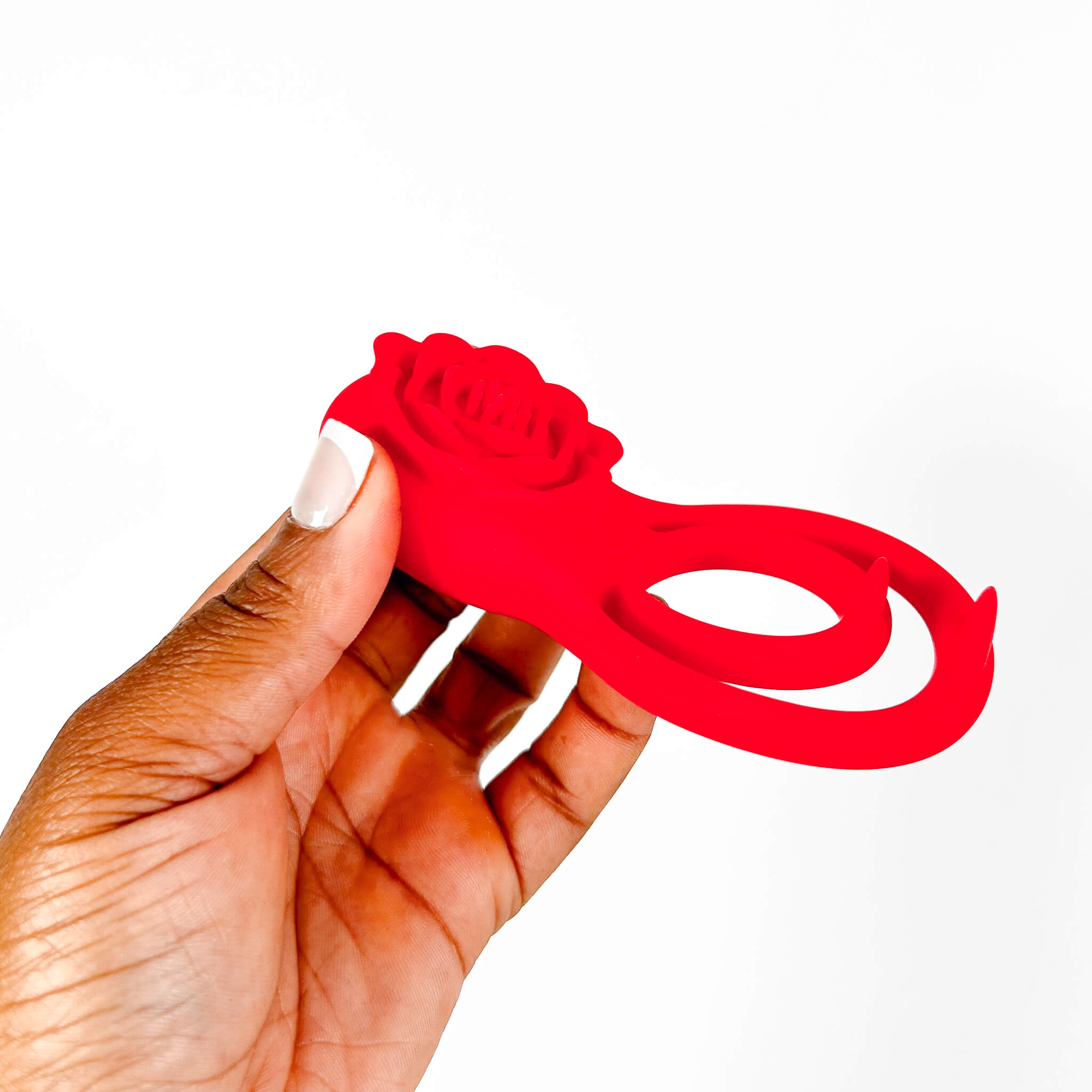 Red rose-shaped vibrating rose cock ring held by a hand on a white background